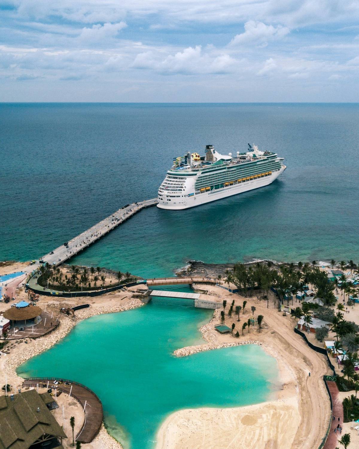 Cruise ship docked beside a turquoise private island lagoon